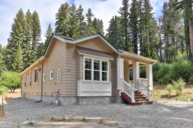 a view of a house with a yard and large tree
