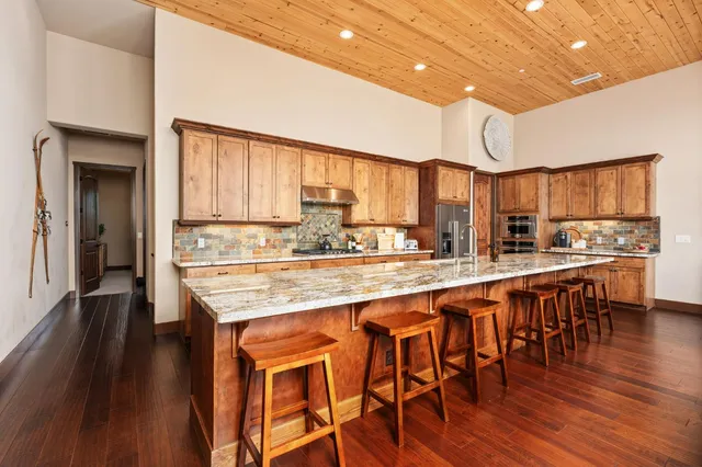 a kitchen with stainless steel appliances granite countertop wooden floors and wooden cabinets