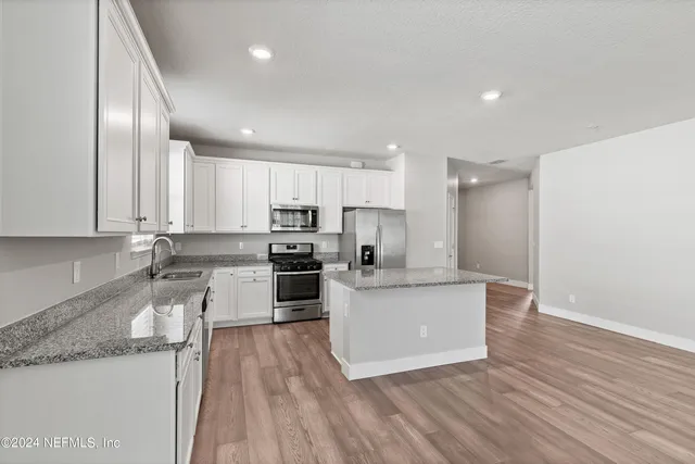 a kitchen with granite countertop a sink cabinets and stainless steel appliances