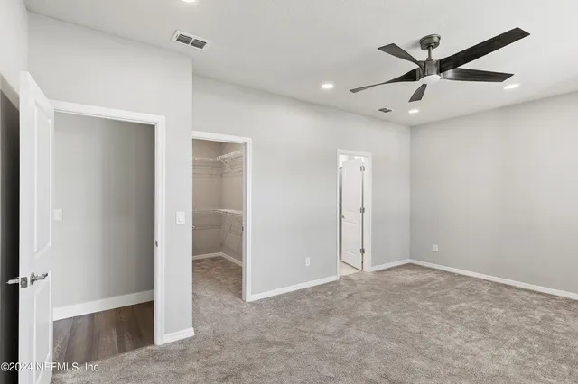 an empty room with closet and a ceiling fan