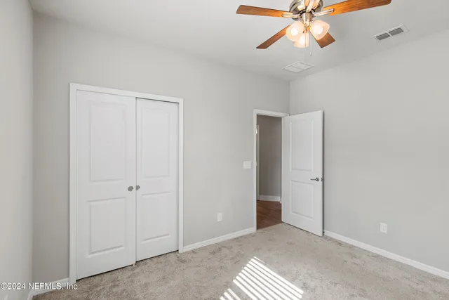 a view of an empty room and chandelier fan