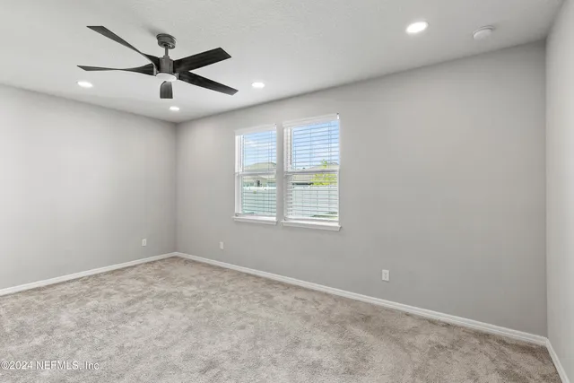 an empty room with a window and a fan