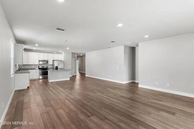 a view of kitchen with refrigerator stove and wooden floor