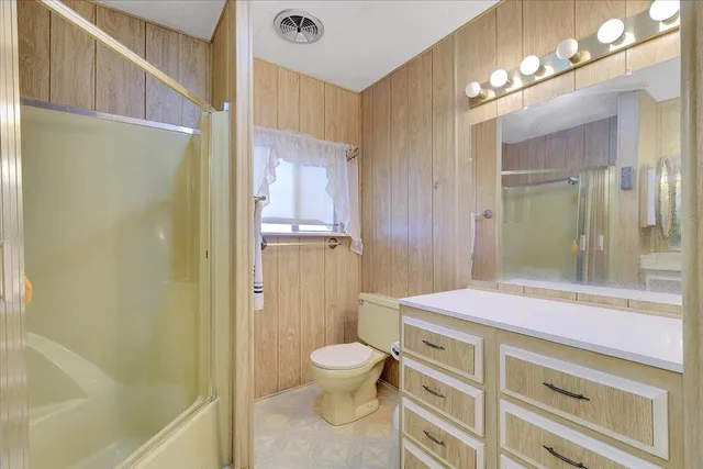 a bathroom with a granite countertop sink toilet a large mirror a shower and vanity