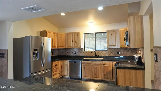 a kitchen with stainless steel appliances granite countertop a refrigerator a sink and a stove