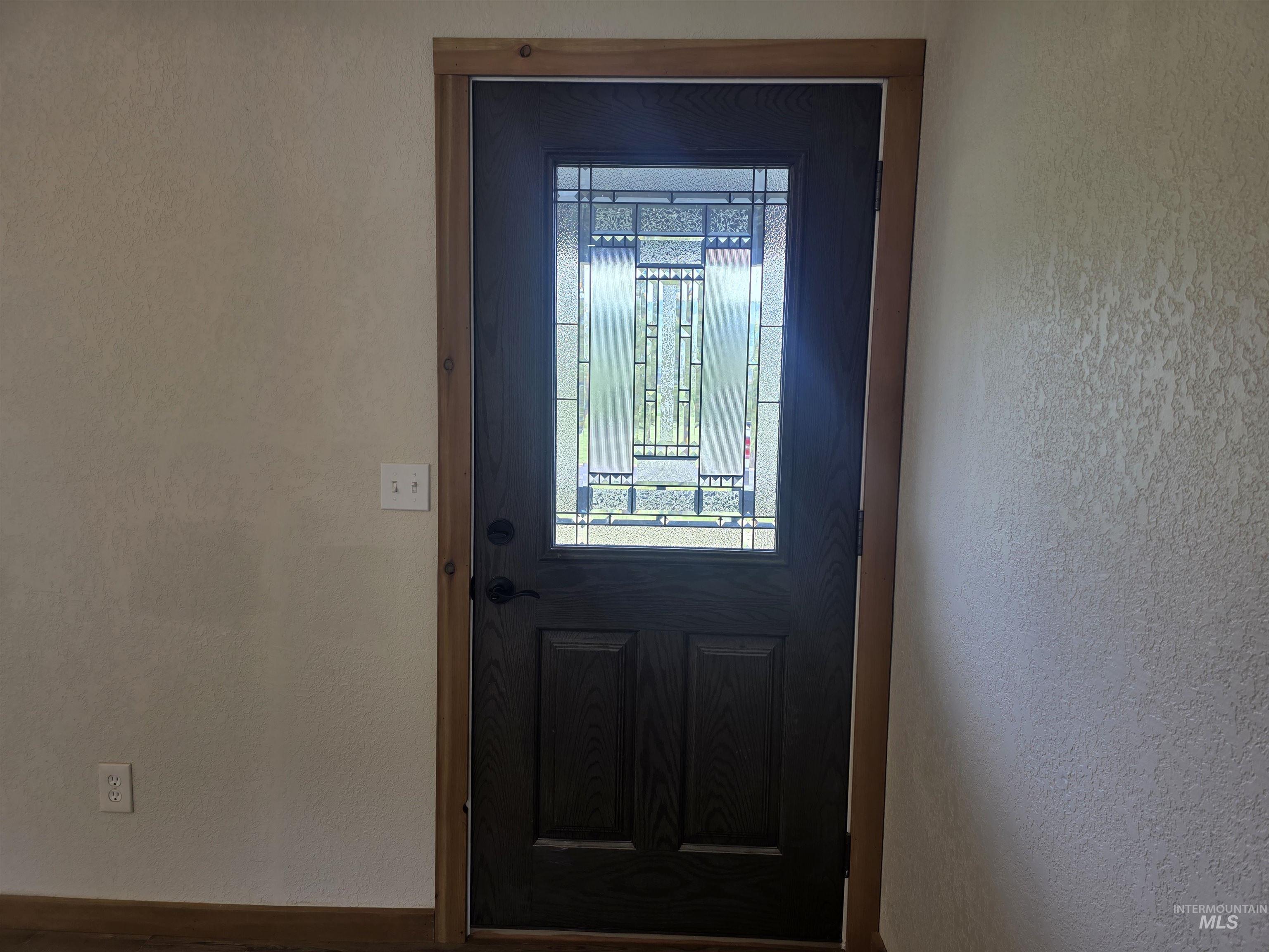 310 Fir Road Kamiah, ID 83536 - Photo 10 of 32 Dark paneled entry door with decorative glass insert, complemented by natural wood trim