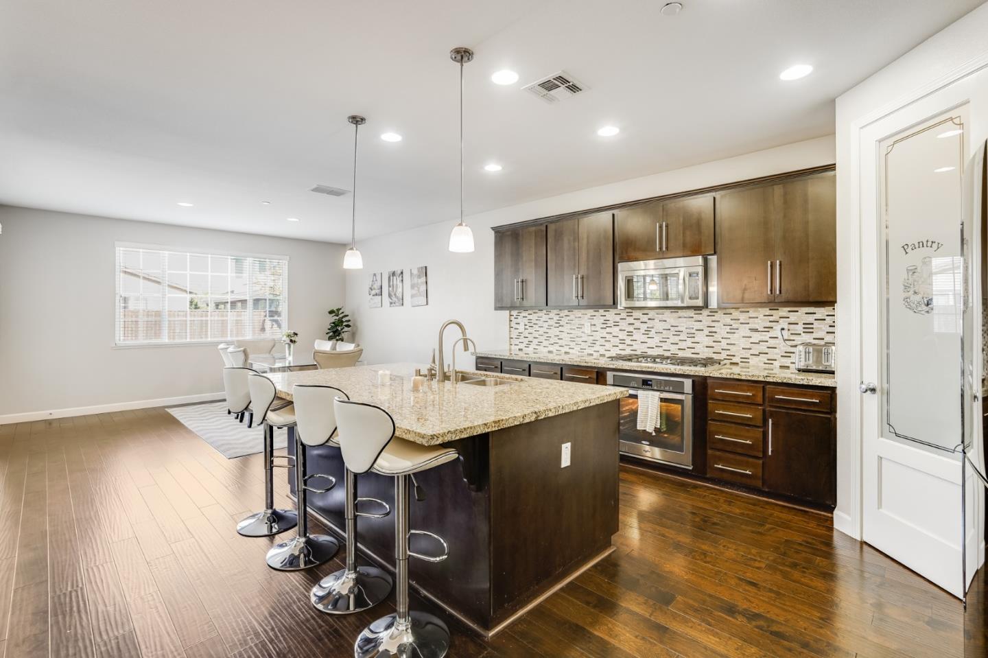 333 Calle Cerro Morgan Hill, CA 95037 - Photo 10 of 45 a open kitchen with stainless steel appliances kitchen island granite countertop a sink dishwasher a stove a refrigerator and island with wooden floor