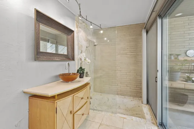 a bathroom with a granite countertop sink a mirror and shower