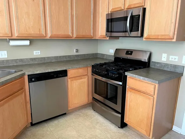 a kitchen with stainless steel appliances granite countertop white cabinets and a stove top oven