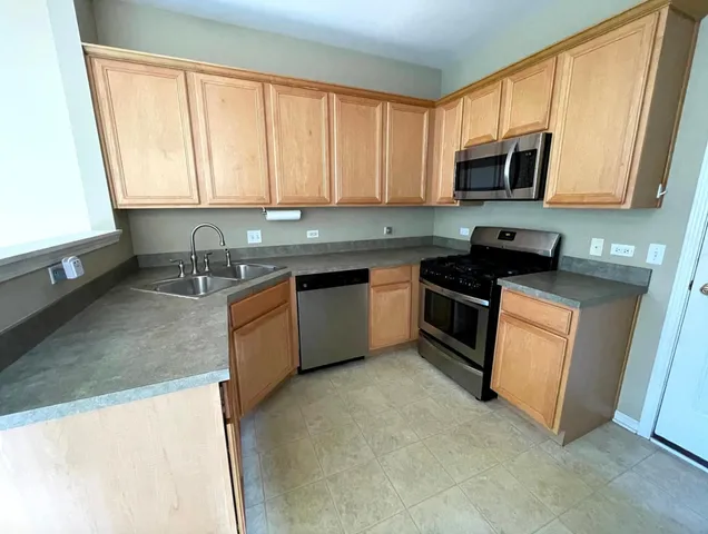 a kitchen with stainless steel appliances granite countertop a stove a sink and a microwave
