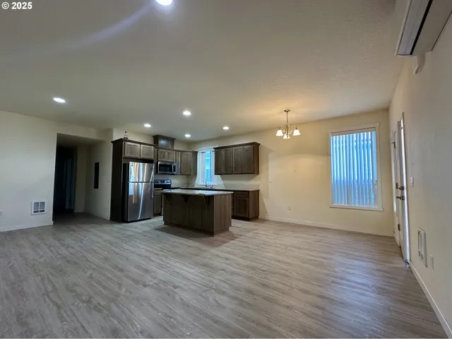 a view of kitchen with kitchen island wooden floor center island and stainless steel appliances