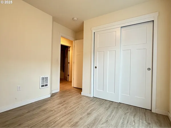 a view of an empty room with wooden floor and closet