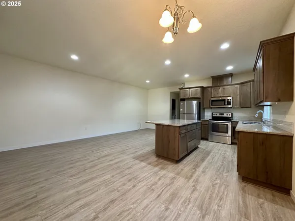 a kitchen with stainless steel appliances granite countertop a stove top oven a sink dishwasher and wooden floor