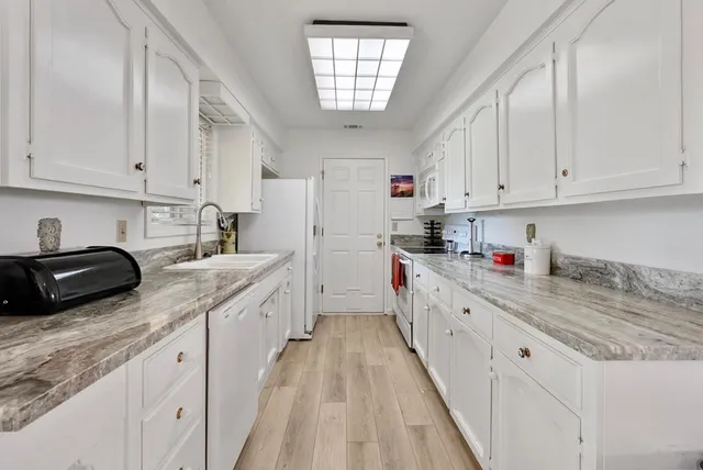 a kitchen with granite countertop white cabinets and white appliances