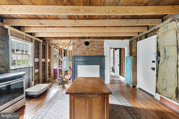 a view of an empty room with wooden floor and a fireplace