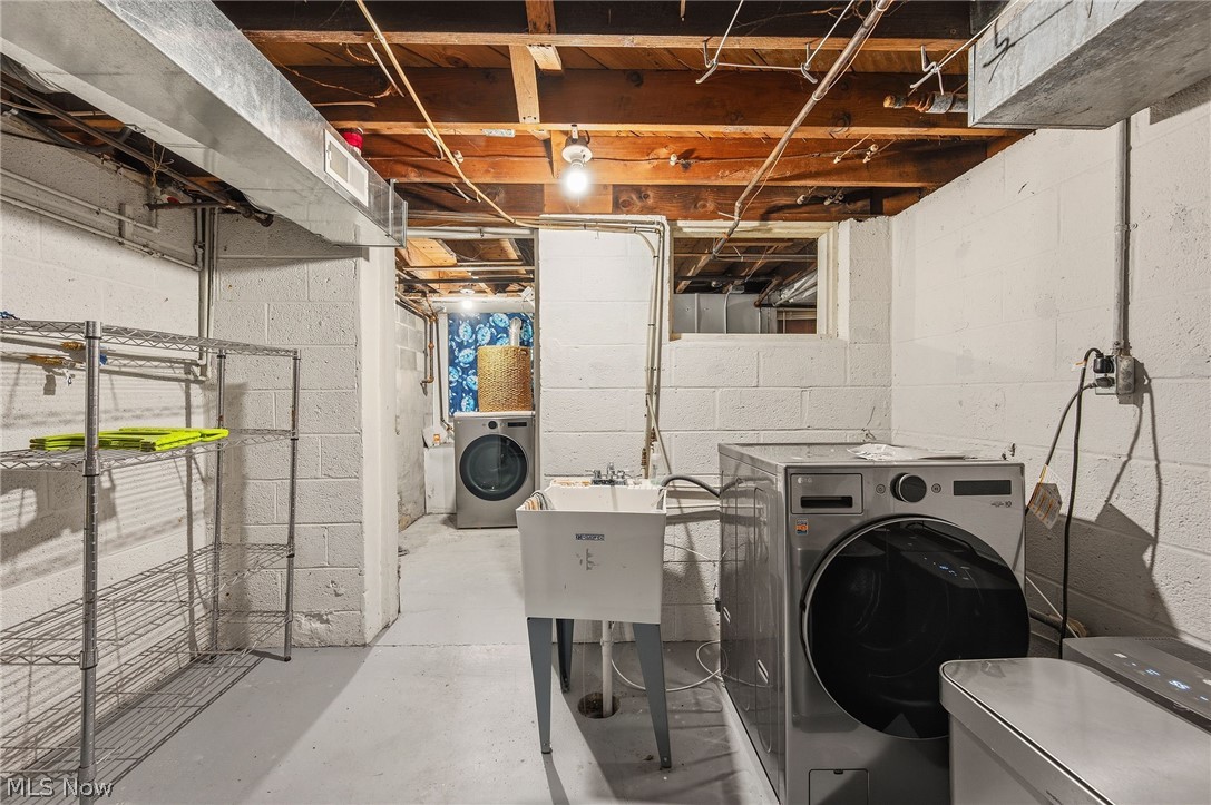 7750 Lewis Road Olmsted Falls, OH 44138 - Photo 39 of 50 Laundry area featuring a utility sink, concrete block walls, exposed ceiling joists, and a front-loading washing machine