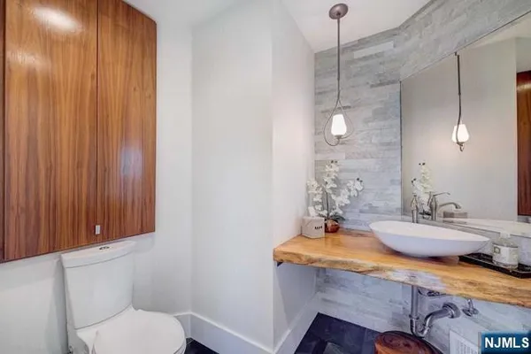 a bathroom with a granite countertop sink a toilet and mirror