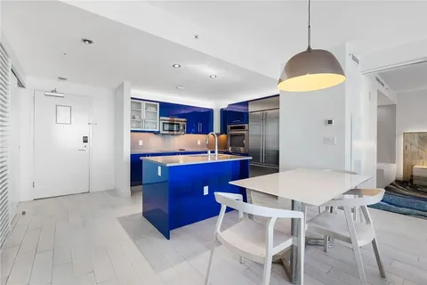 a kitchen with stainless steel appliances granite countertop a stove a refrigerator and a dining table with wooden floor