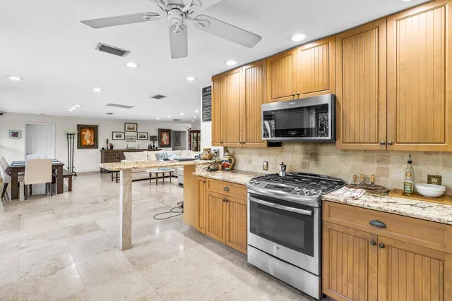 a kitchen with stainless steel appliances granite countertop a stove top oven a sink dishwasher a dining table and chairs with wooden floor