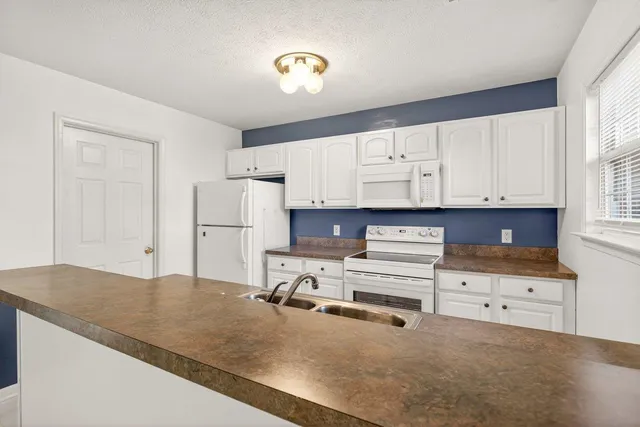 a kitchen with granite countertop a refrigerator sink and cabinets