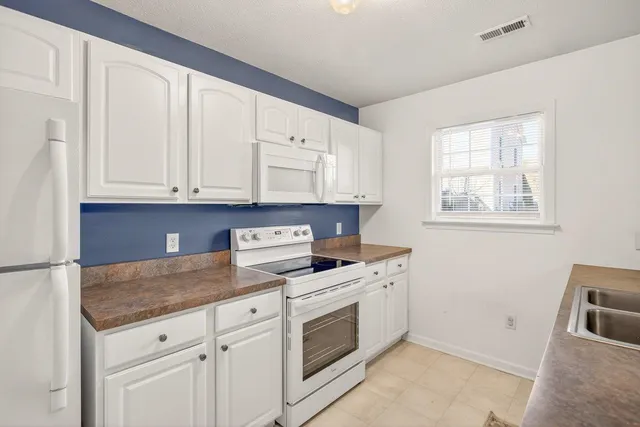 a kitchen with granite countertop white cabinets and white appliances
