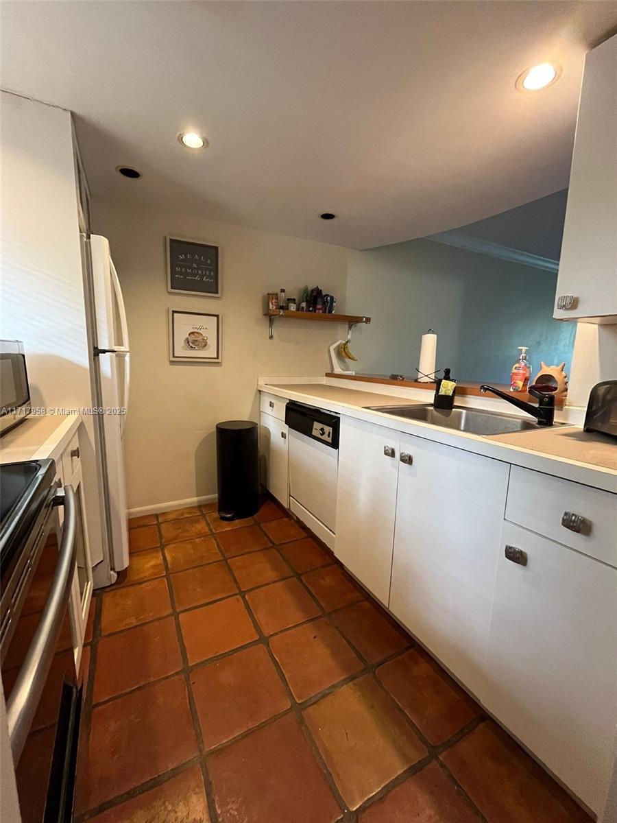 812 Southwest 9th St Circle, Unit 101 Boca Raton, FL 33486 - Photo 11 of 17 a kitchen with a sink a stove and cabinets