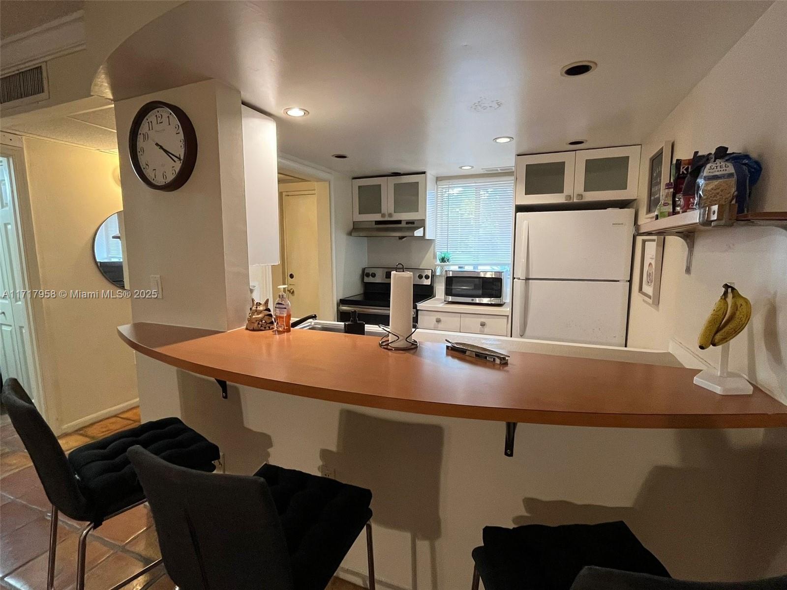 812 Southwest 9th St Circle, Unit 101 Boca Raton, FL 33486 - Photo 3 of 17 a kitchen with a table chairs and a refrigerator
