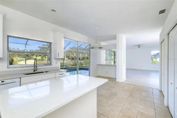 a large white kitchen with granite countertop a sink and a large window