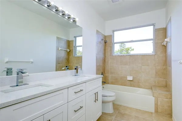 a bathroom with a granite countertop sink a toilet and bathtub
