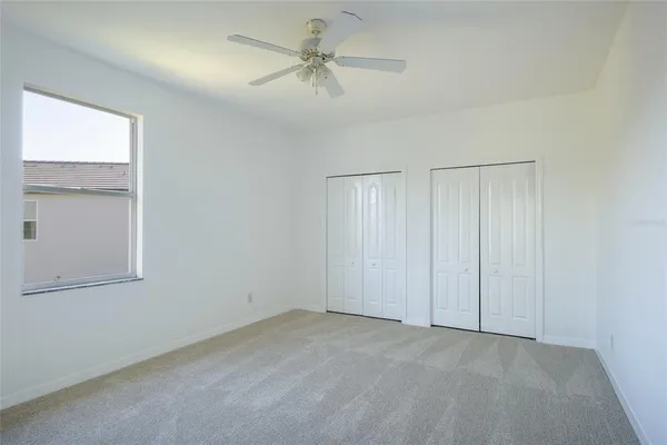 an empty room with a ceiling fan and a window