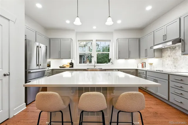 a kitchen with stainless steel appliances granite countertop a table chairs refrigerator and microwave