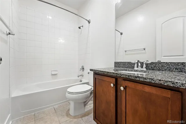 a bathroom with a granite countertop sink a toilet and bathtub