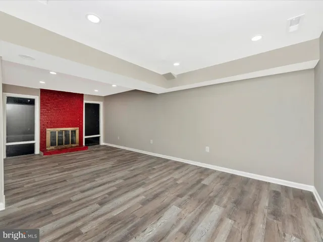 a view of an empty room with wooden floor closet and a window