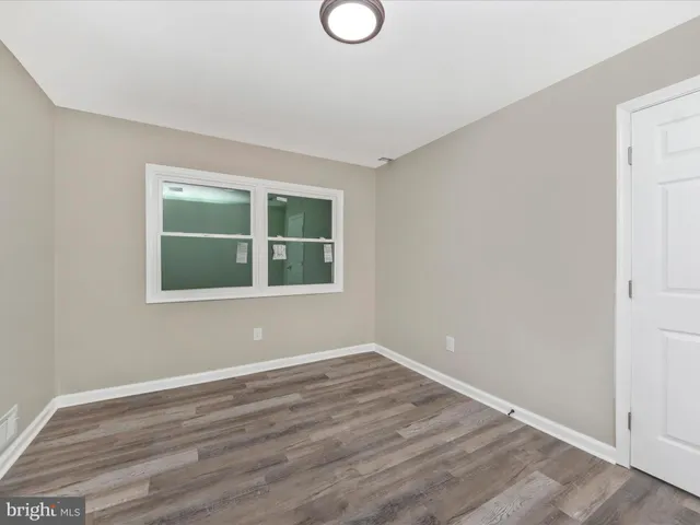 a view of empty room with wooden floor and windows