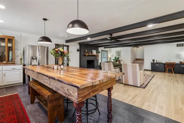 a dining hall with stainless steel appliances granite countertop a kitchen island a stove a sink a refrigerator and a wooden floors