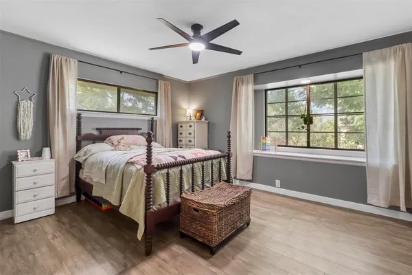 a bedroom with a bed couch and windows