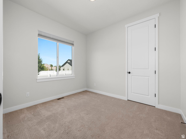 2786 West Hancock Street, Unit 198 Mapleton, UT 84664 - Photo 14 of 33 Neutral-toned room featuring a large window with white trim, light-colored carpet flooring, and a white paneled door with a matte black handle