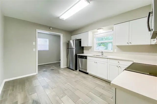 a kitchen with granite countertop a refrigerator sink and cabinets