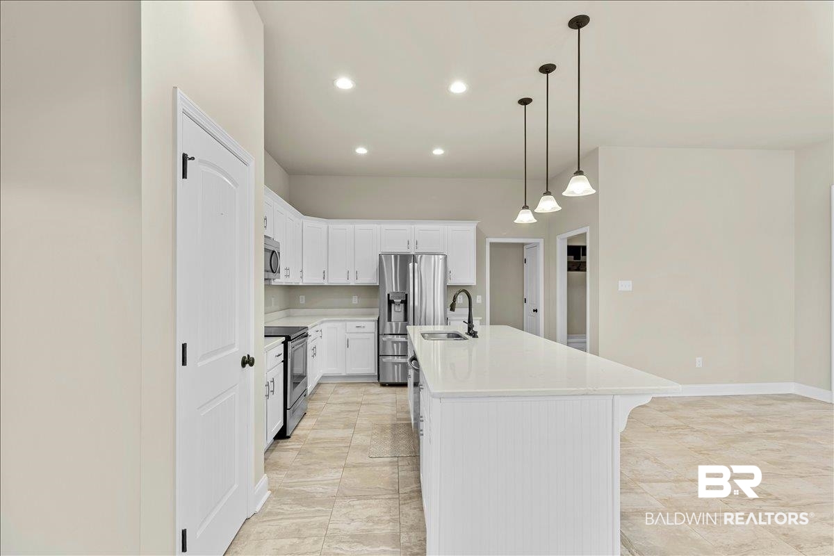 1112 Stella Road Foley, AL 36535 - Photo 10 of 33 Kitchen with a center island with sink, white cabinetry, decorative light fixtures, stainless steel appliances, and light stone counters