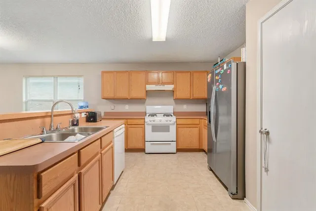a kitchen with a sink refrigerator and cabinets
