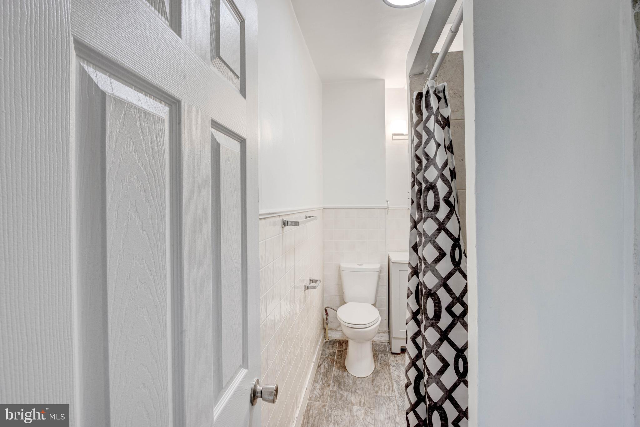 3438 Belair Road Baltimore, MD 21213 - Photo 23 of 36 a bathroom with a toilet and a shower curtain