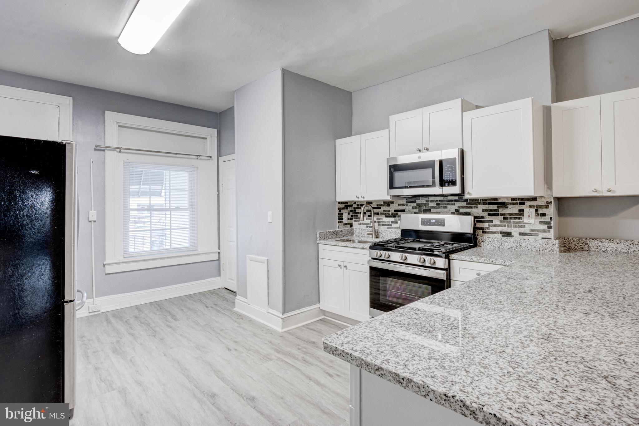 3438 Belair Road Baltimore, MD 21213 - Photo 7 of 36 a kitchen with kitchen island a stove a sink and a microwave