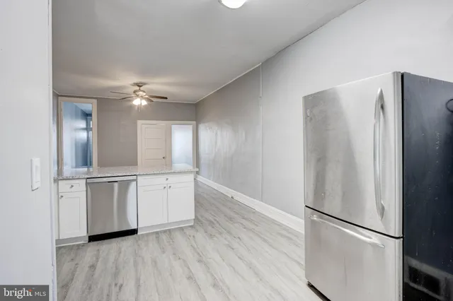 a kitchen with stainless steel appliances a refrigerator and a hard wood floor
