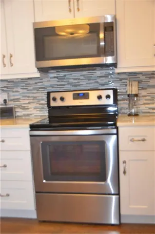 a kitchen with granite countertop white cabinets and stainless steel appliances
