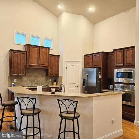 a kitchen with stainless steel appliances granite countertop a refrigerator a stove a sink a dining table and chairs