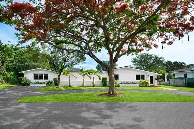 a front view of a house with garden and trees