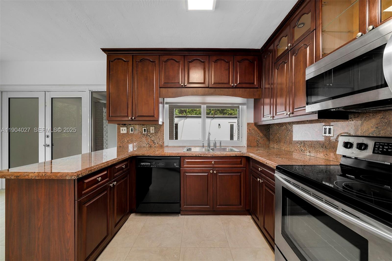 7575 Southwest 134th Street Pinecrest, FL 33156 - Photo 7 of 28 a kitchen with stainless steel appliances granite countertop a sink stove and microwave