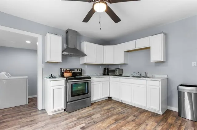 a kitchen with stainless steel appliances a stove a sink and white cabinets