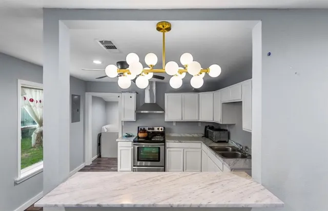 a kitchen with stainless steel appliances granite countertop a sink a stove top oven a chimney and a window