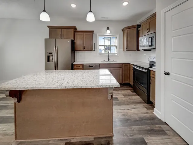 a kitchen with stainless steel appliances granite countertop a sink and a refrigerator